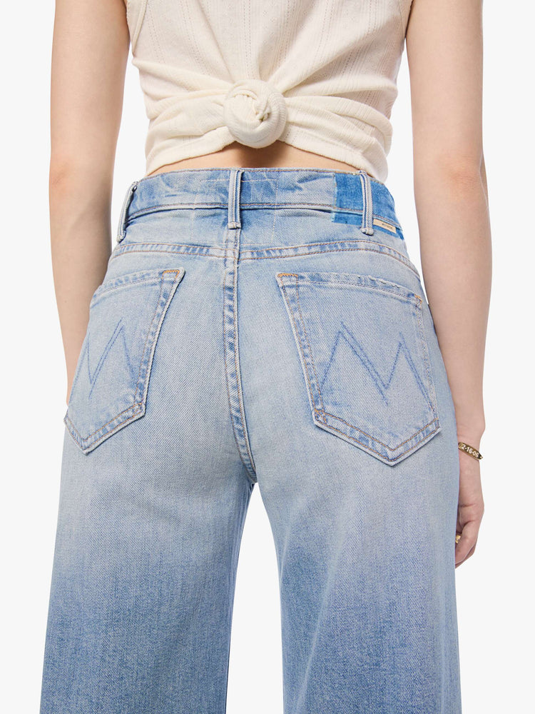 Close up view of a petite woman in a light blue wide leg jeans with a high rise, zip fly, 32-inch inseam and a clean hem.