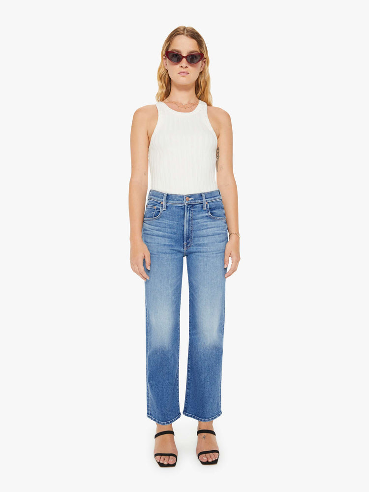 Front view of a petite woman high-waisted jeans with a wide straight leg, zip fly and clean ankle-length inseam in a mid blue wash.