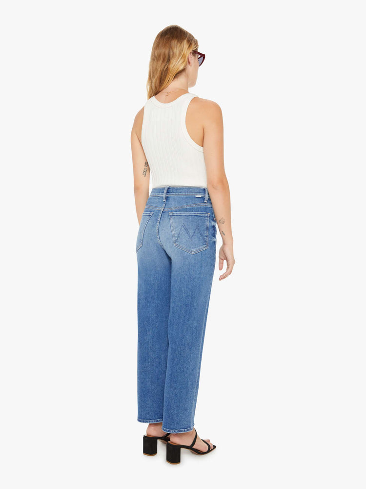 Back view of a petite woman high-waisted jeans with a wide straight leg, zip fly and clean ankle-length inseam in a mid blue wash.