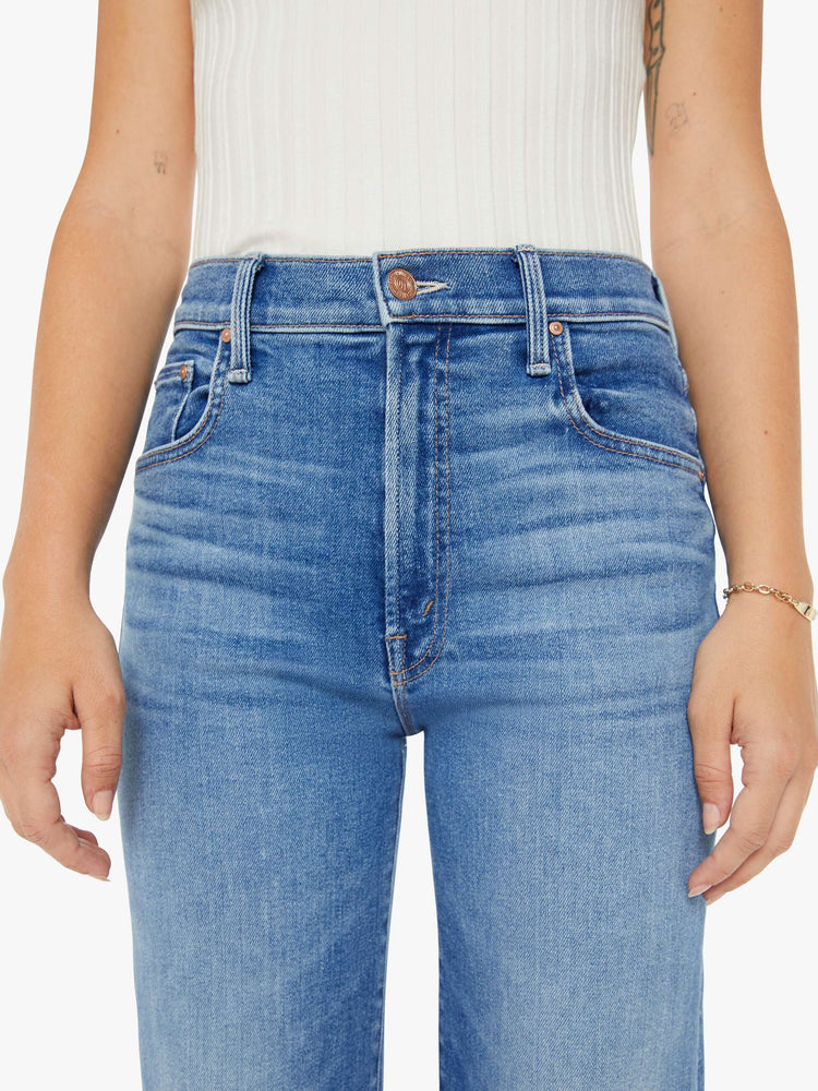 Waist view of a petite woman high-waisted jeans with a wide straight leg, zip fly and clean ankle-length inseam in a mid blue wash.