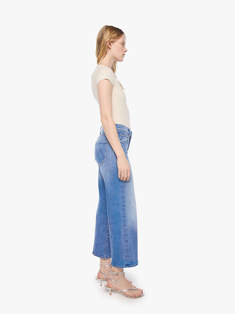 Side view of a petite woman in a mid-rise jeans with a wide straight leg, zip fly and clean ankle-length inseam.