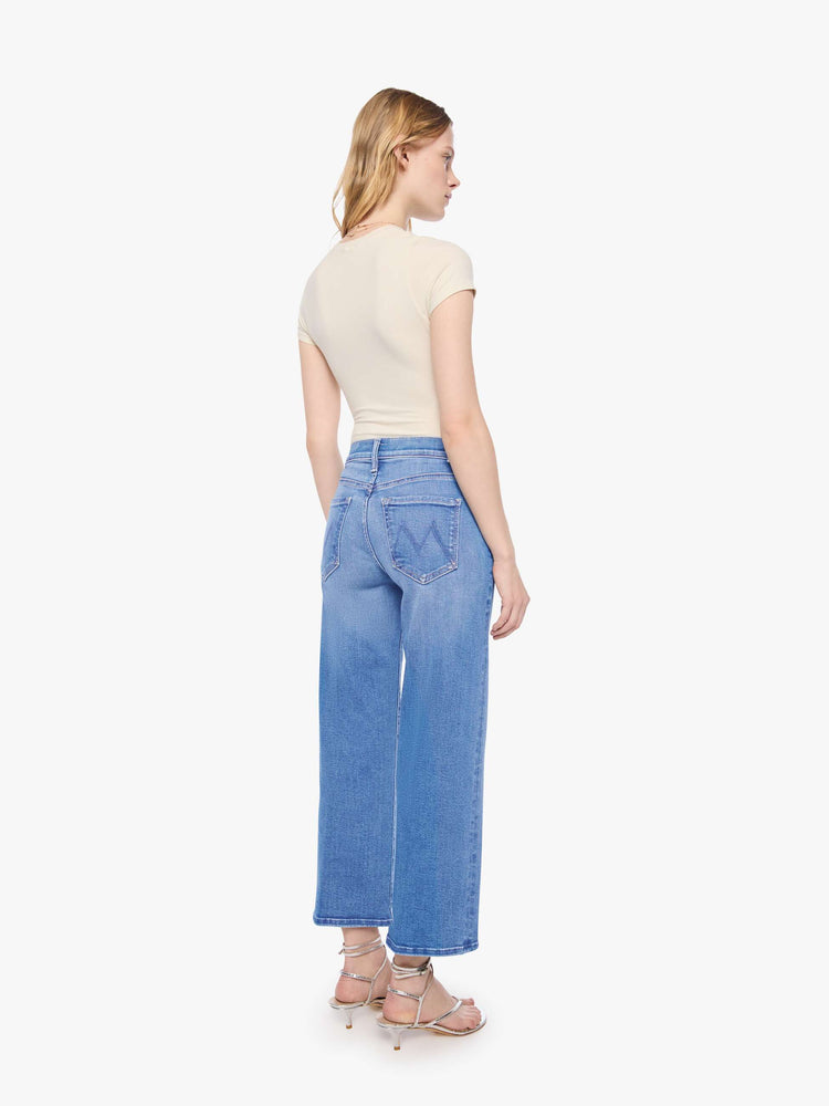 Back view of a petite woman in a mid-rise jeans with a wide straight leg, zip fly and clean ankle-length inseam.