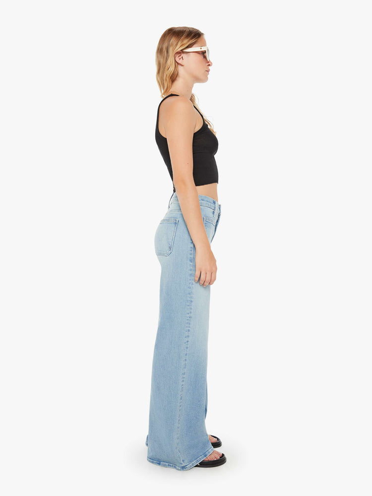 Side view of a womens light blue jean featuring a high rise, wide leg, and front patch pockets.