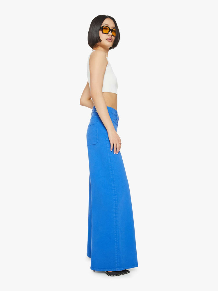 Side view of a woman in a bright sea blue wide leg pants with a high rise, patch pockets and a clean hem.