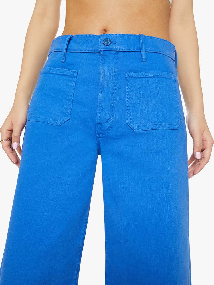 Close up view of a woman in a bright sea blue wide leg pants with a high rise, patch pockets and a clean hem.