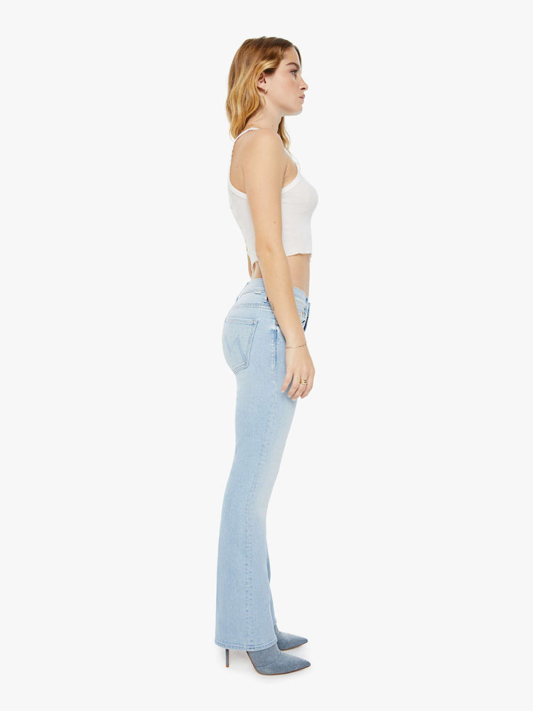 Side view of a woman in light-blue high waisted bootcut jeans that have a clean hem with subtle whiskering and fading throughout.