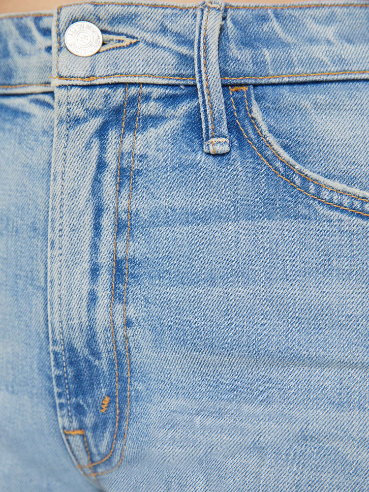 Swatch view of a woman in light blue 70s-inspired high waisted wide leg jeans that have a frayed hem with whiskering, fading and distressed details.