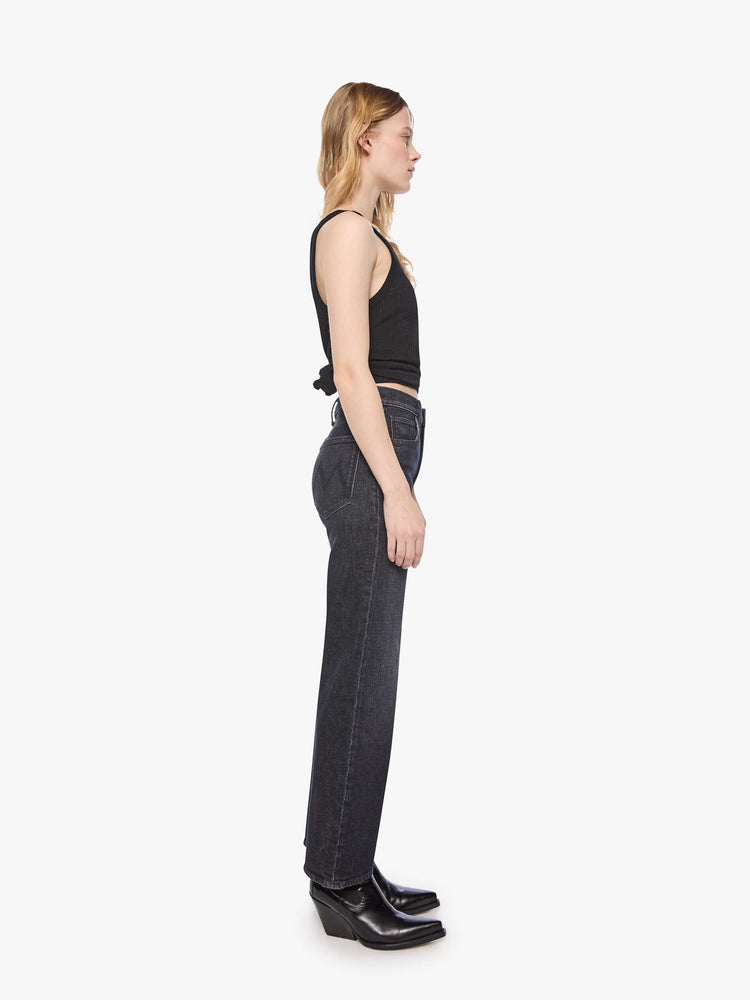 Side view of a petite woman in a washed black igh-rise jeans with a straight leg, zip fly and a 29-inch inseam with a clean hem.