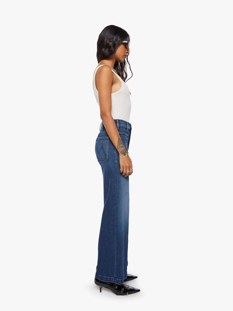 Side view of a woman in a dark blue wide leg jeans with a high rise, zip fly, patch pockets, 30-inch inseam and clean hem.