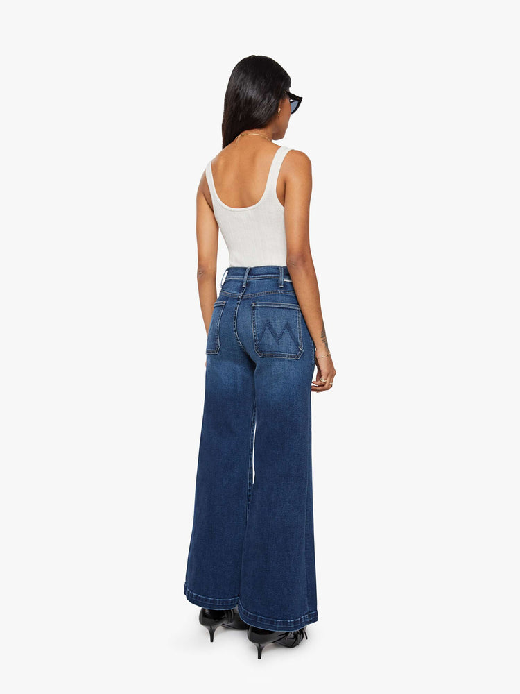 Back view of a woman in a dark blue wide leg jeans with a high rise, zip fly, patch pockets, 30-inch inseam and clean hem.