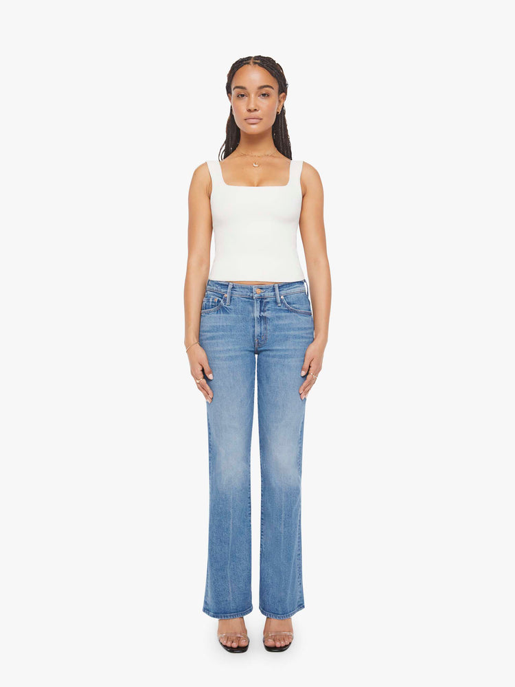 Front view of a petite woman in a mid blue bootcut jeans with a mid rise, zip fly and a long 29-inch inseam with a clean hem. 