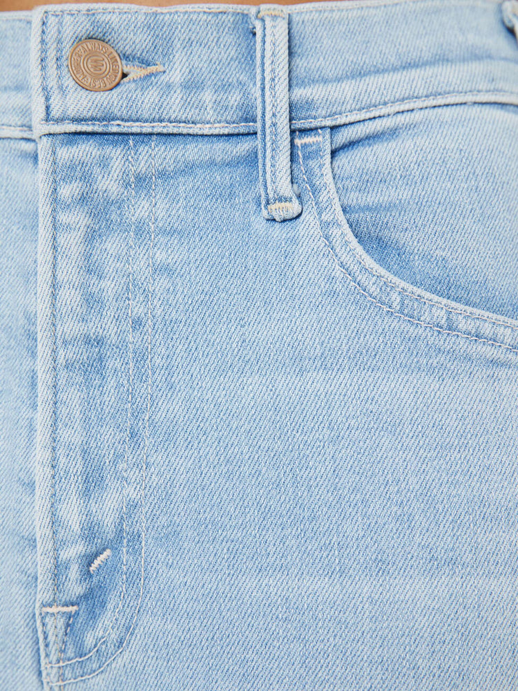Swatch view of a petite woman in a light blue denim high-rise flare has an ankle-length inseam and a raw hem.