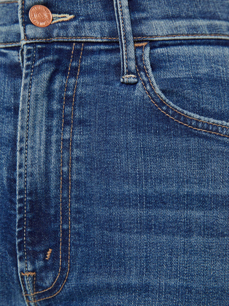 Close up swatch view of a petite woman mid blue wash jean with a high-rise flare has an ankle-length inseam and a raw hem.