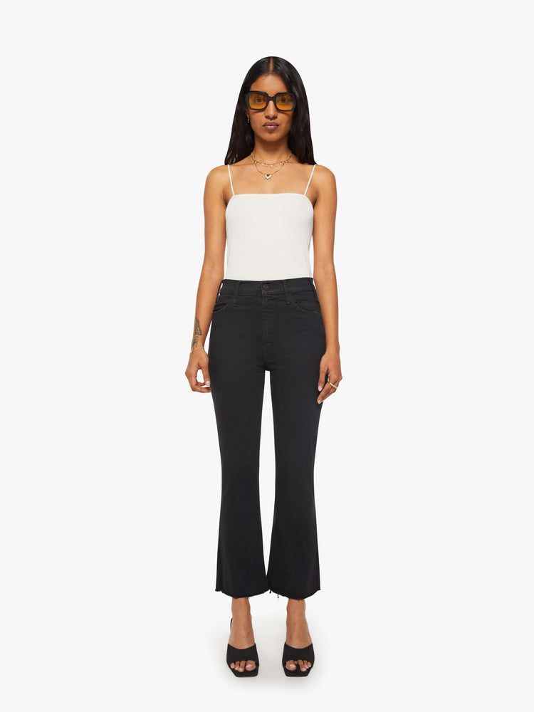 Front view of a woman black denim high-rise flare has an ankle-length inseam and a frayed hem.