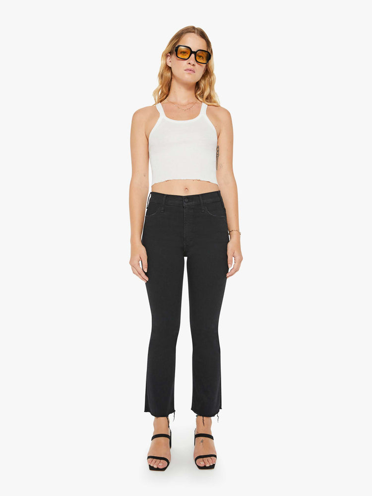 Front view of a woman black denim high-rise flare has an ankle-length inseam and a frayed hem.