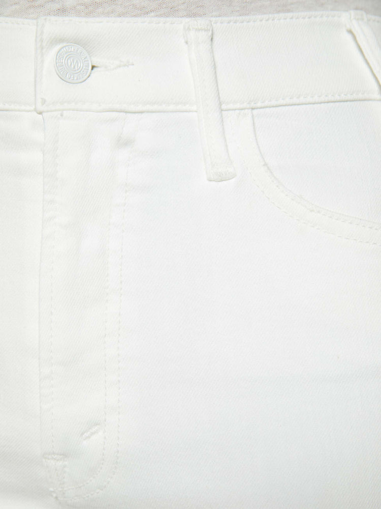 Detailed view of a woman in white high-rise flare jeans that have an ankle-length inseam and a raw hem.