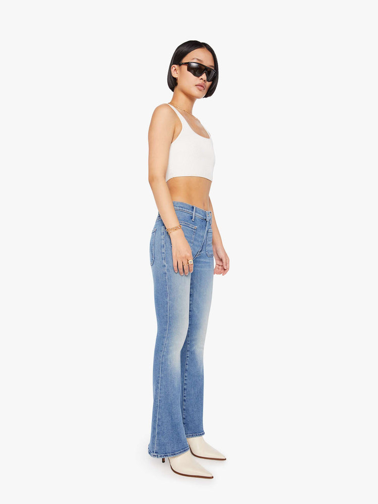 Side angle view of a petite woman flare has a mid rise, zip fly, patch pockets, a 29-inch inseam and a clean hem.