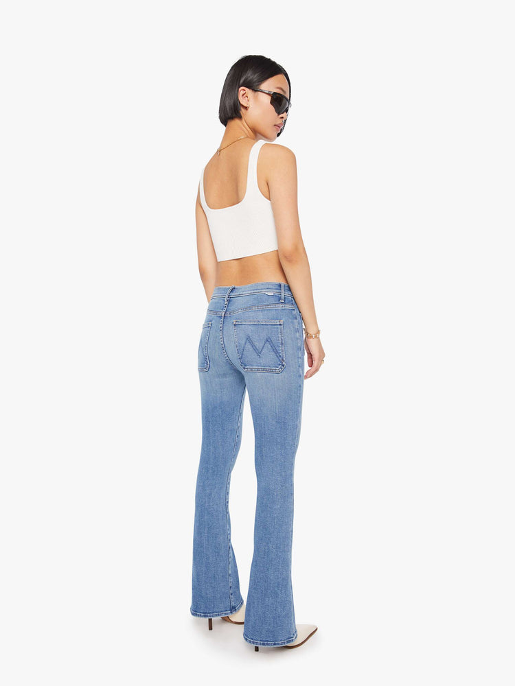 Back view of a petite woman flare has a mid rise, zip fly, patch pockets, a 29-inch inseam and a clean hem.