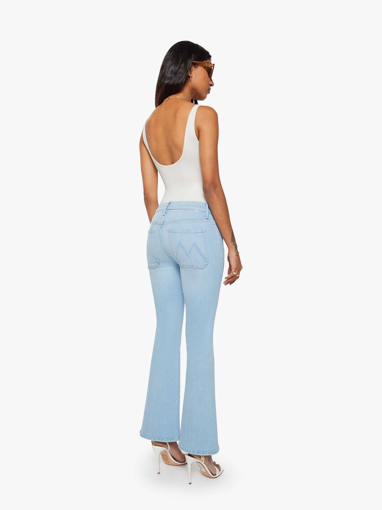 Back view of a petite woman in a light blue flare with a mid rise, zip fly, patch pockets, a 28-inch inseam and a clean hem. 