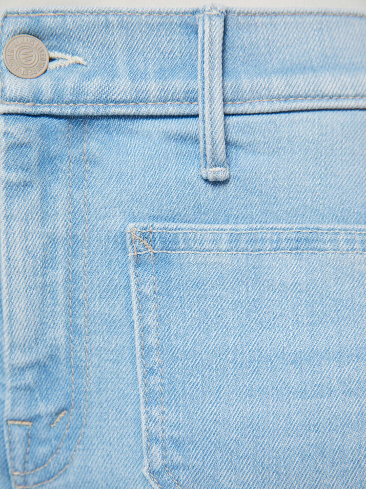 Swatch view of a petite woman in a light blue flare with a mid rise, zip fly, patch pockets, a 28-inch inseam and a clean hem. 