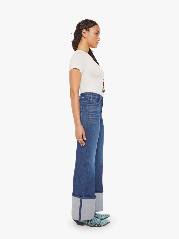 Side view of a petite woman in a dark blue wide leg jeans with a high rise, zip fly and a long 30-inch inseam with an extra-wide cuffed hem.