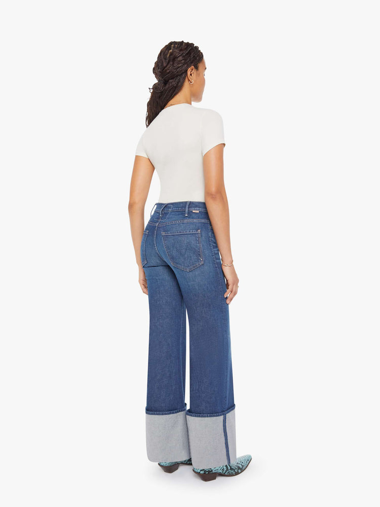 Back view of a petite woman in a dark blue wide leg jeans with a high rise, zip fly and a long 30-inch inseam with an extra-wide cuffed hem.