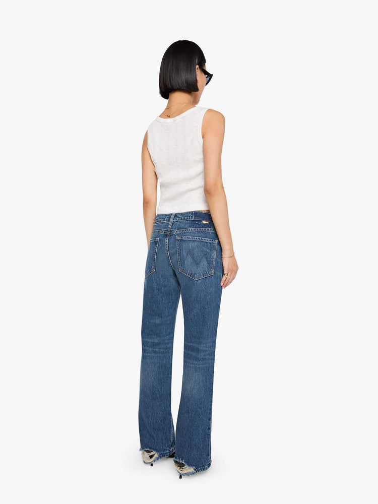 Back view of a petite woman in a  straight leg with a bit of a kick, the jean features a mid rise, full-length inseam and clean hem in a classic blue.