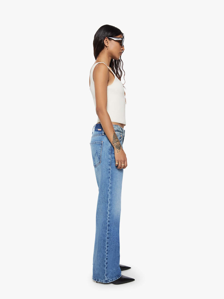 Side view of a petite woman in a  straight leg with a bit of a kick, the jean features a mid rise, full-length inseam and clean hem in med blue wash.