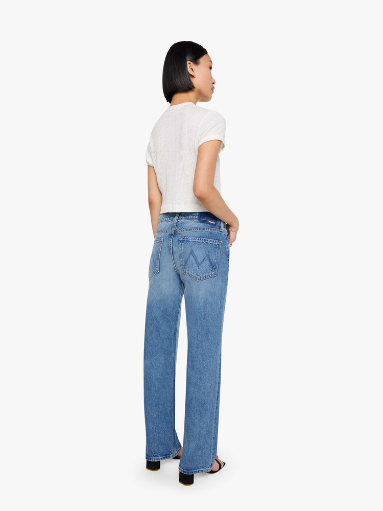 Back view of a petite woman in a  straight leg with a bit of a kick, the jean features a mid rise, full-length inseam and clean hem in med blue wash.