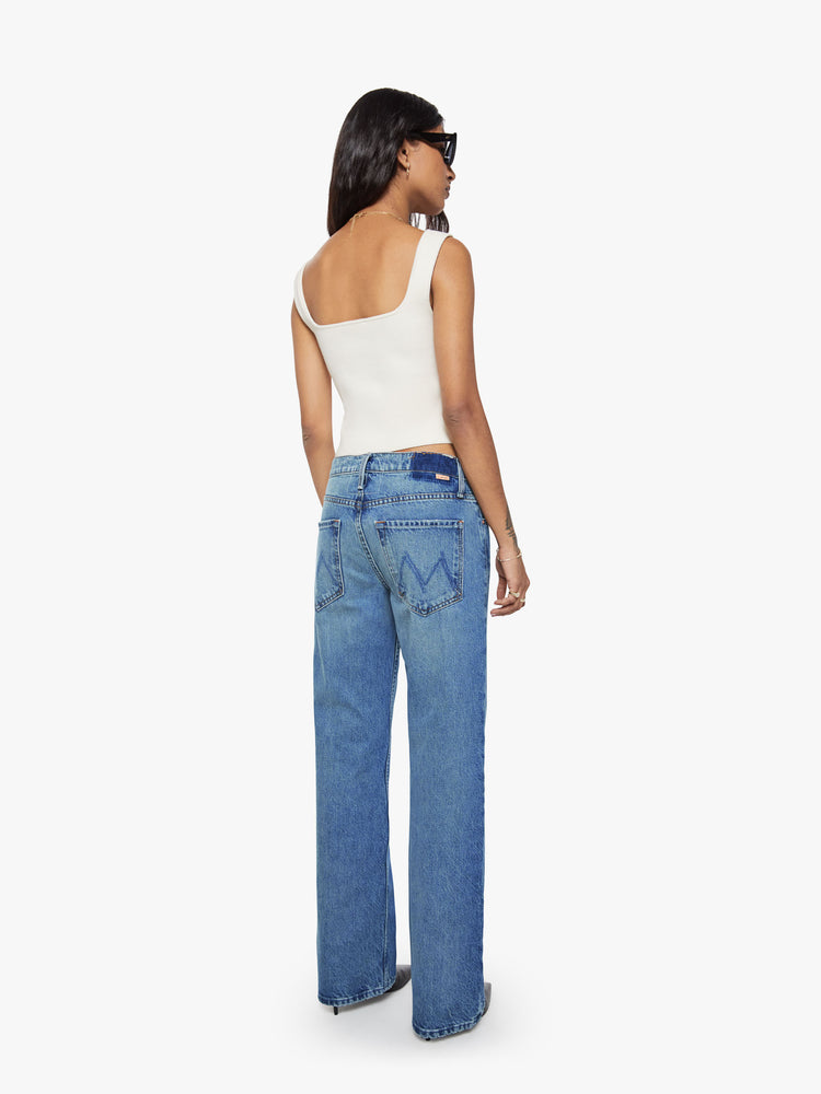 Back view of a petite woman in a  straight leg with a bit of a kick, the jean features a mid rise, full-length inseam and clean hem in med blue wash.