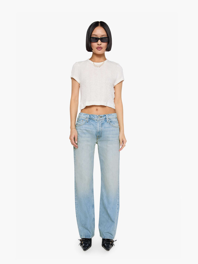 Front view of a woman in a sun faded indigo blue straight leg jean with a bit of a kick, the jean features a mid rise, 29-inch inseam, a subtly distressed hem and relaxed fit.