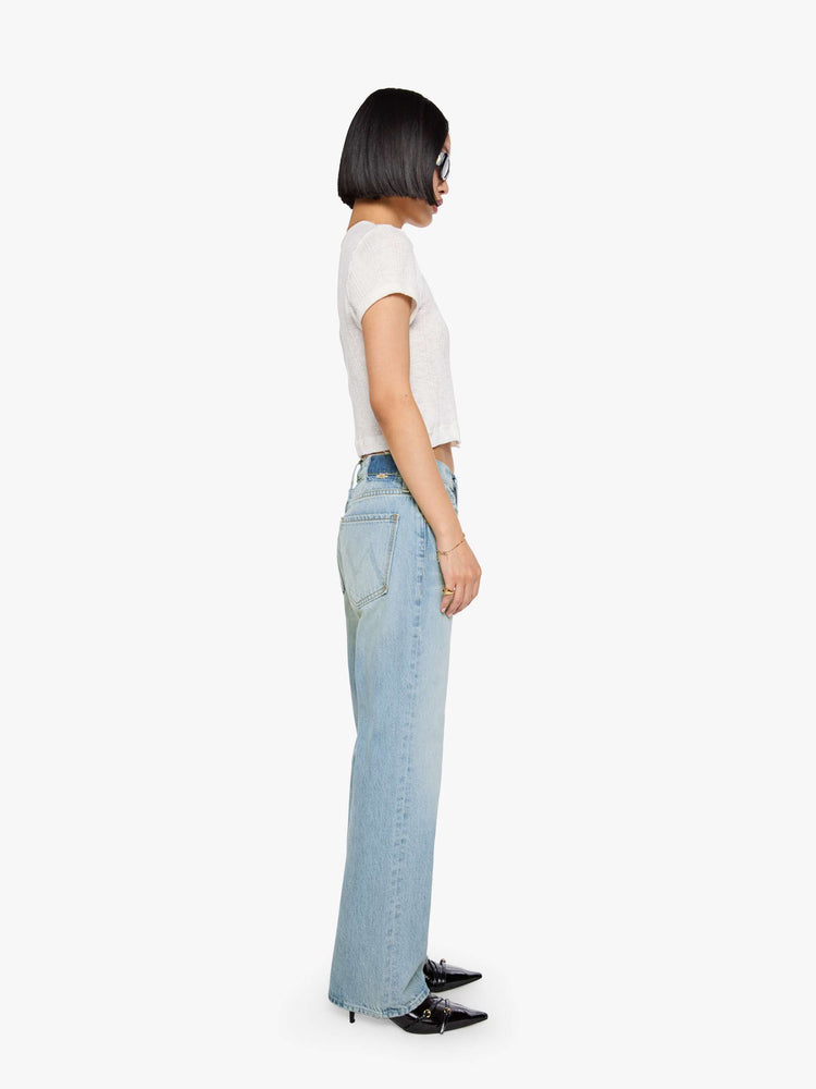 Side view of a woman in a sun faded indigo blue straight leg jean with a bit of a kick, the jean features a mid rise, 29-inch inseam, a subtly distressed hem and relaxed fit.