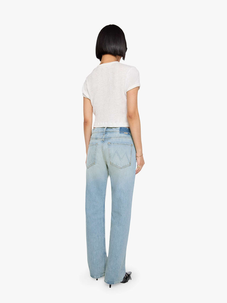 Back view of a woman in a sun faded indigo blue straight leg jean with a bit of a kick, the jean features a mid rise, 29-inch inseam, a subtly distressed hem and relaxed fit.