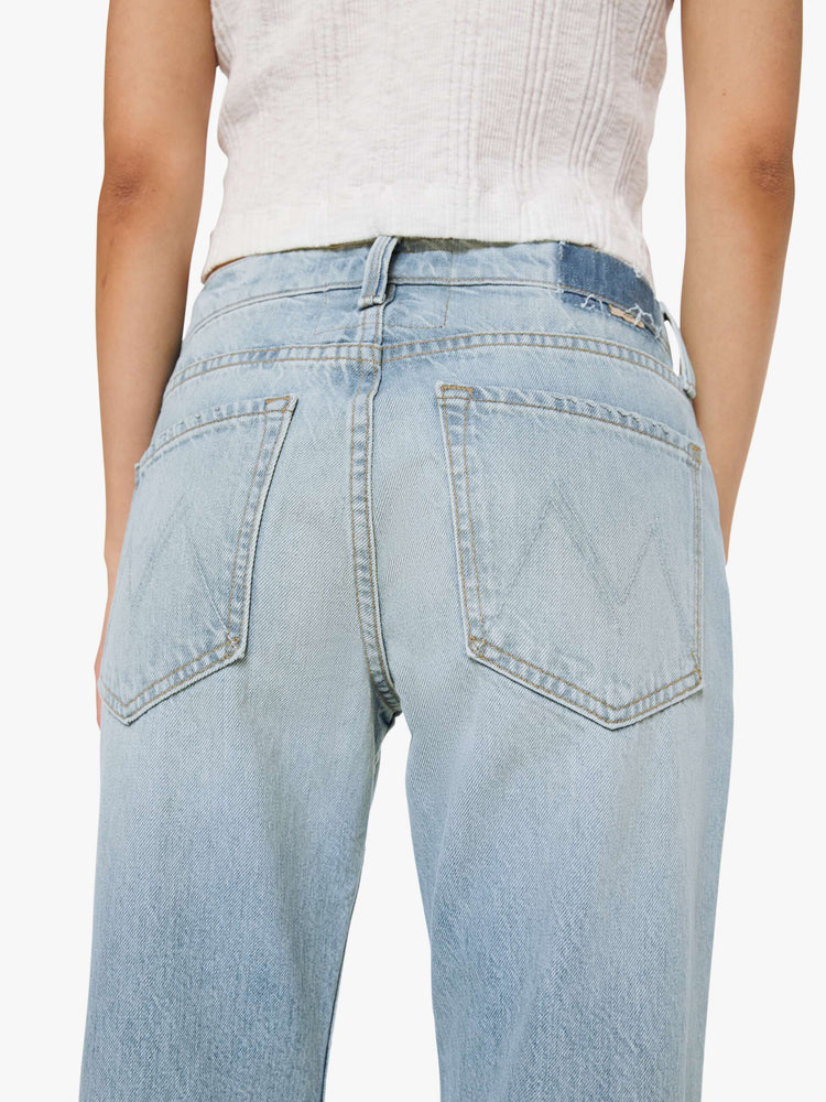 Back close up view of a woman in a sun faded indigo blue straight leg jean with a bit of a kick, the jean features a mid rise, 29-inch inseam, a subtly distressed hem and relaxed fit.