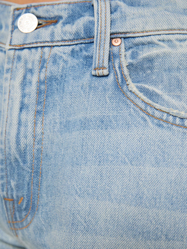 Close up view of a woman in a sun faded indigo blue straight leg jean with a bit of a kick, the jean features a mid rise, 29-inch inseam, a subtly distressed hem and relaxed fit.