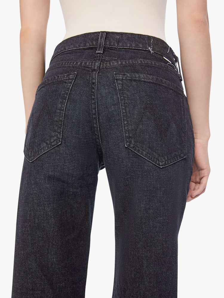 Close up view of a woman in a black straight leg with a bit of a kick, the jean features a mid rise, 30-inch inseam, clean hem and relaxed fit. 