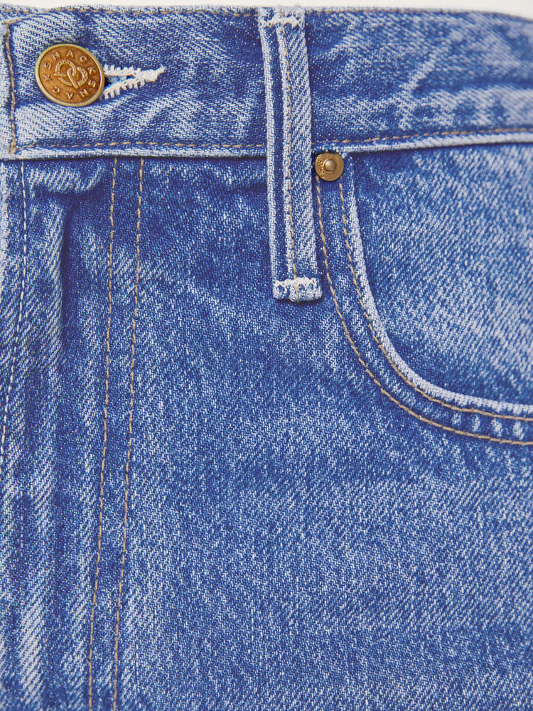 Swatch view of petite woman in a mid blue high waisted jean with a wide leg  with a curved outer seam and a long 28-inch inseam with a clean hem. 