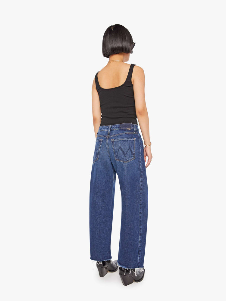 Back view of a petite woman in a mid-rise jeans designed to sit lower on the hips with a full barrel leg, zip fly, 26.25-inch inseam and a frayed hem.