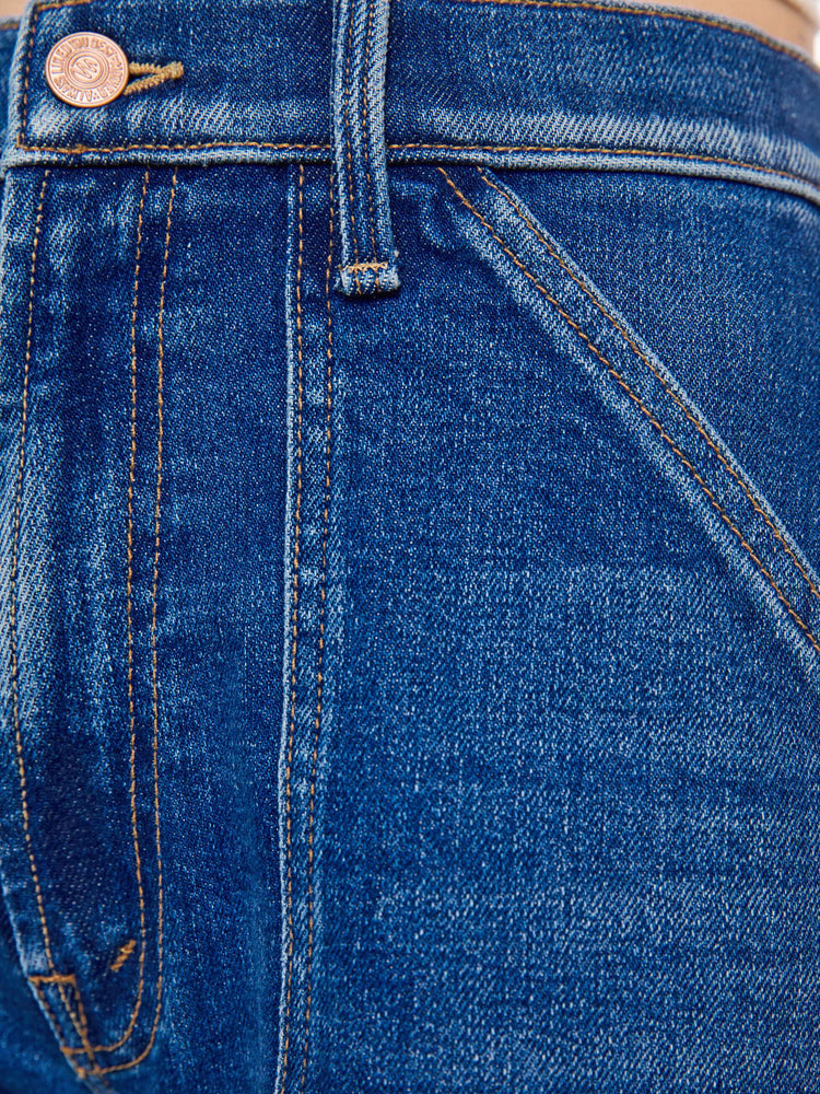 Swatch view of a woman in a mid blue super high-rise jeans with a loose fit, wide leg, patch pockets, zip fly and 30 3/4 inch inseam with a clean hem.