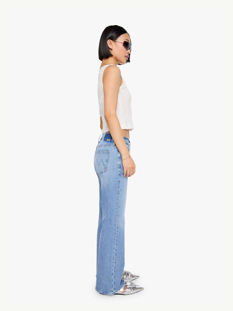 Side  view of a petites woman in a light blue lower-rise bootcut jean with a zip fly, long 29-inch inseam and a clean hem.