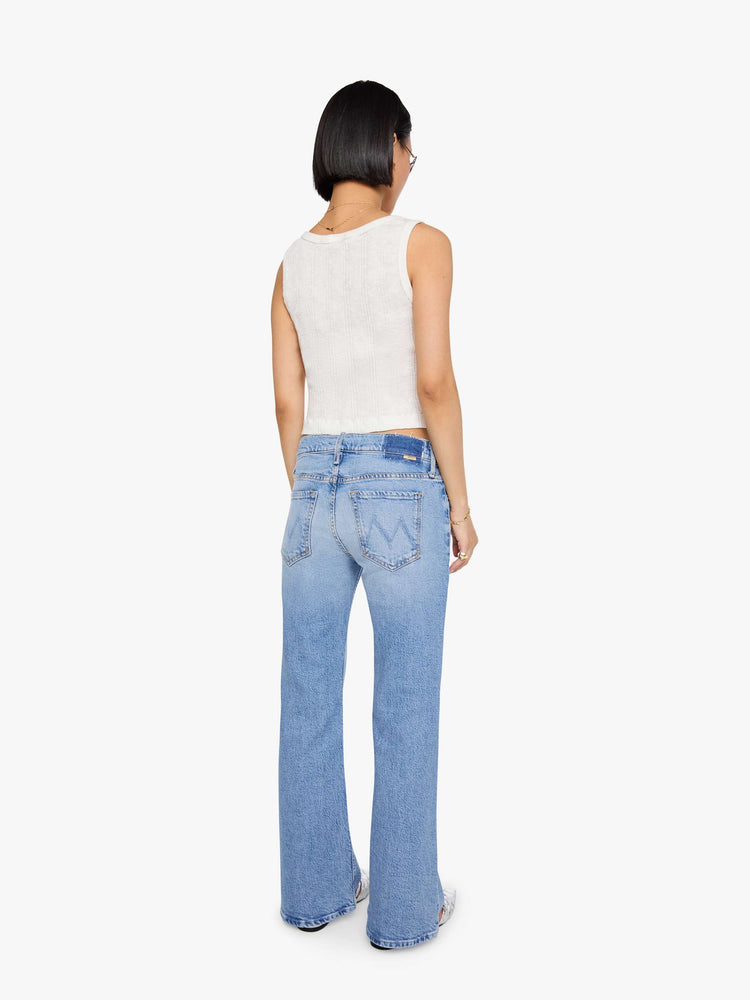 Back  view of a petites woman in a light blue lower-rise bootcut jean with a zip fly, long 29-inch inseam and a clean hem.
