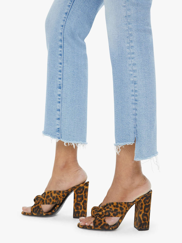 Hem view of a petite woman light blue high-waisted bootcut hits at the ankle with a frayed step-hem.