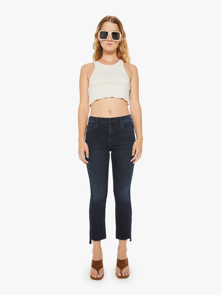 Front view of a petite woman high-waisted bootcut hits at the ankle with a frayed step-hem dark denim jean.