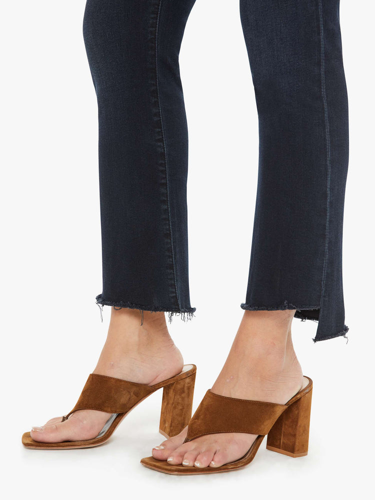Hem close up view of a petite woman high-waisted bootcut hits at the ankle with a frayed step-hem dark denim jean.