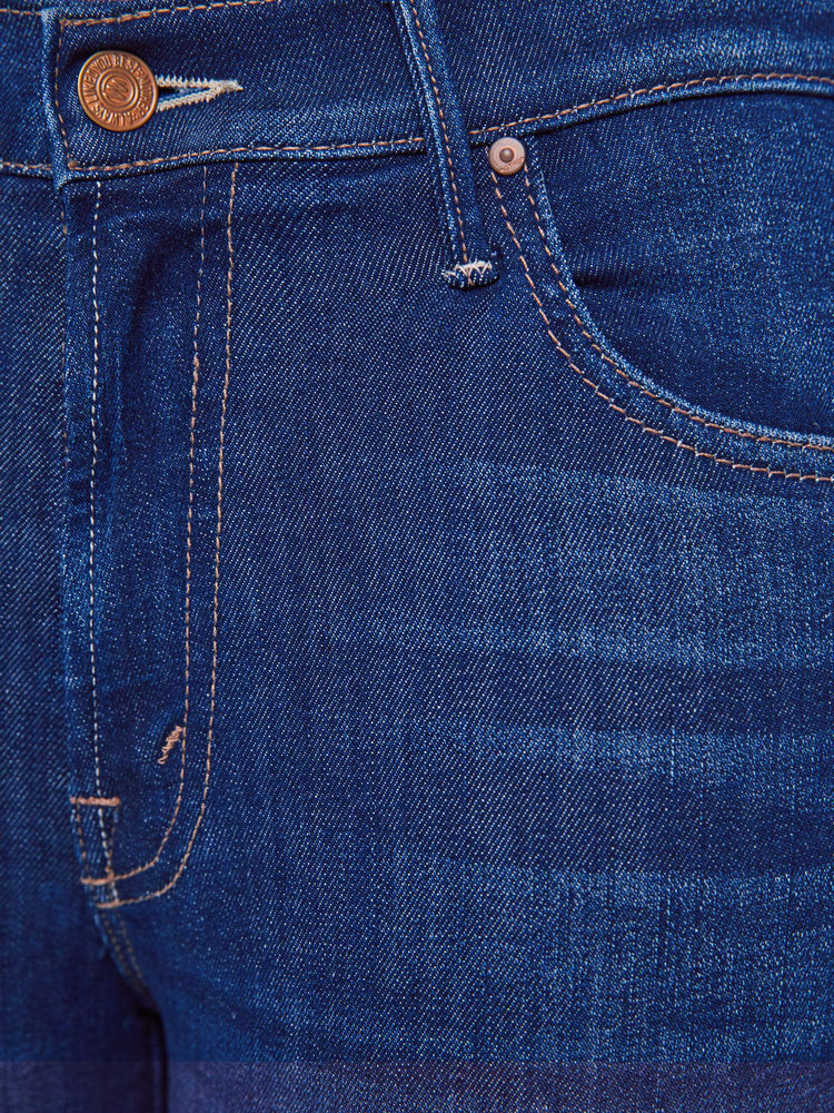 Swatch view of a petite woman in a dark blue wash high-waisted bootcut is cropped at the ankle with a frayed step-hem jean.