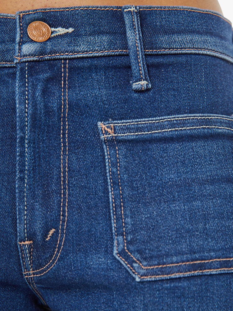 Swatch view of a woman in a dark blue mid-rise jeans with a loose fit, zip fly, wide leg, patch pockets and ankle-length inseam with a clean hem.