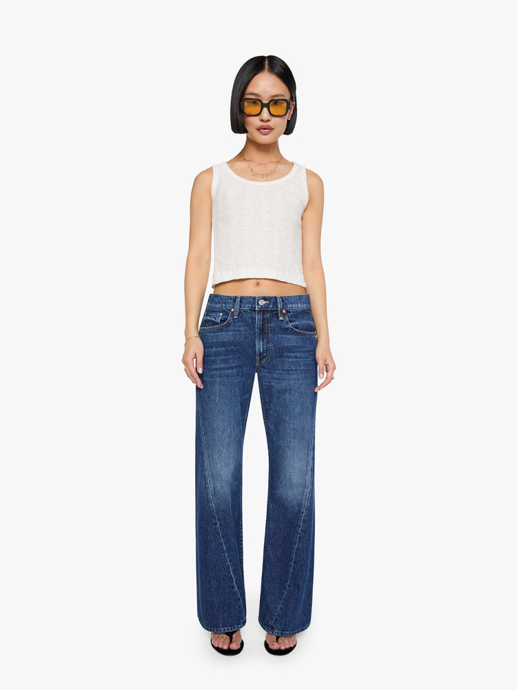 Front view of a petite woman in a mid-rise bootcut with a zip fly, looser leg, twisted outer seam and a long 32-inch inseam with a clean hem.