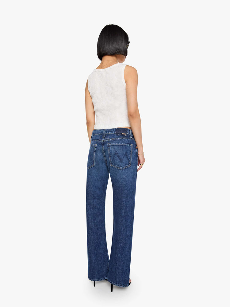 Back view of a petite woman in a mid-rise bootcut with a zip fly, looser leg, twisted outer seam and a long 32-inch inseam with a clean hem.
