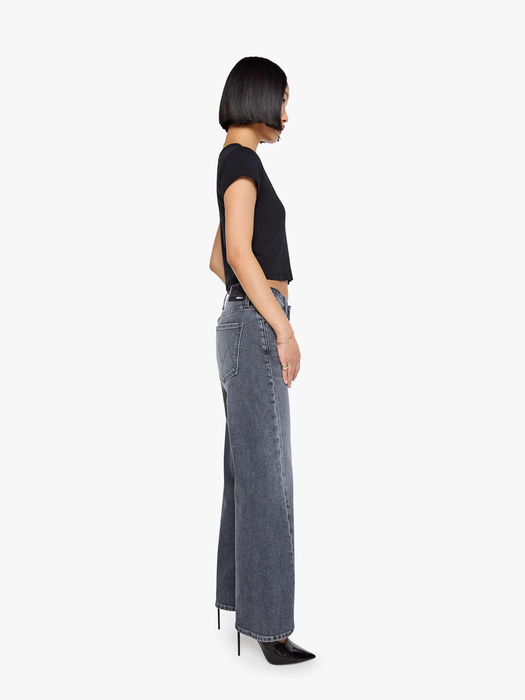 Side view of a woman in a washed grey mid-rise bootcut with a zip fly, looser leg, twisted outer seam and a long 29-inch inseam with a clean hem.