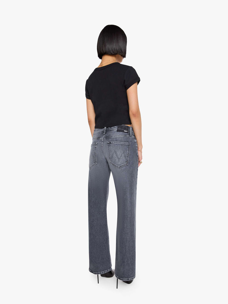 Back view of a woman in a washed grey mid-rise bootcut with a zip fly, looser leg, twisted outer seam and a long 29-inch inseam with a clean hem.